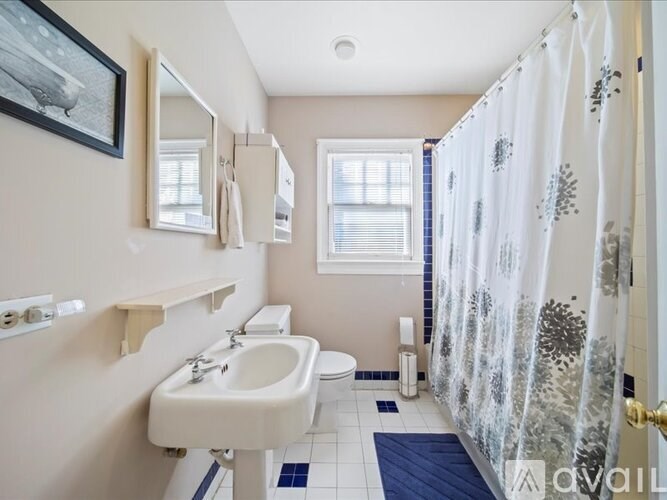 A bathroom with a sink, mirror, toilet, and shower curtain.