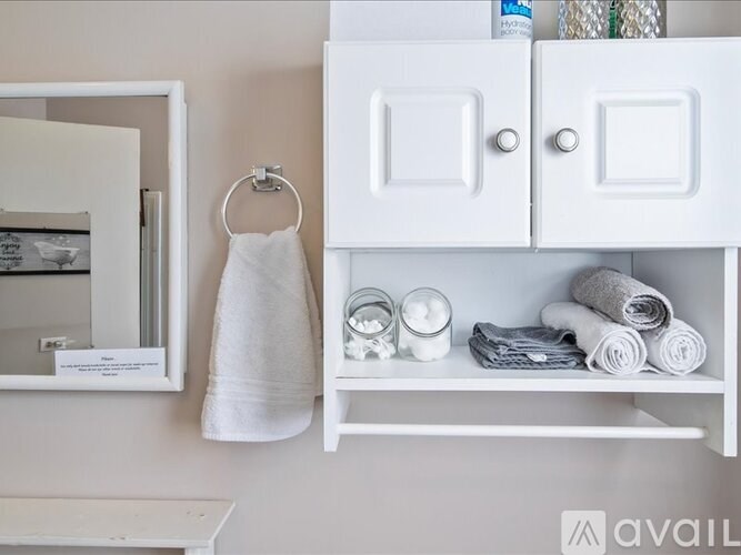 A white bathroom with a towel hanging on a towel ring.