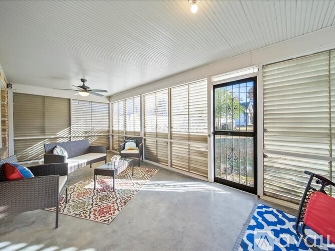 A sunroom with a ceiling fan and sliding glass doors.