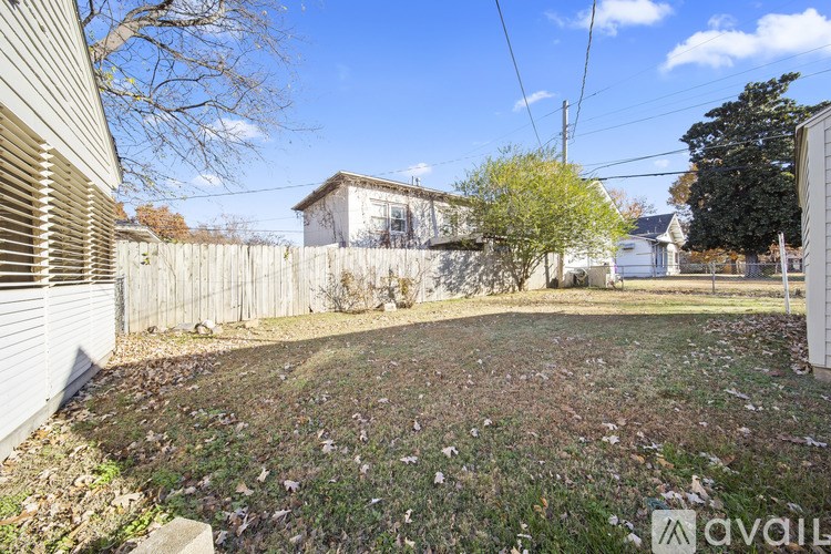 A backyard with a fence and a house in the background.