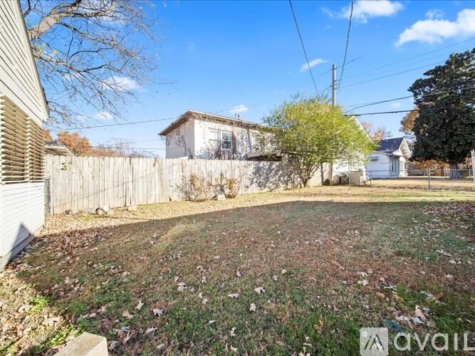 A backyard with a fence and a house in the background.