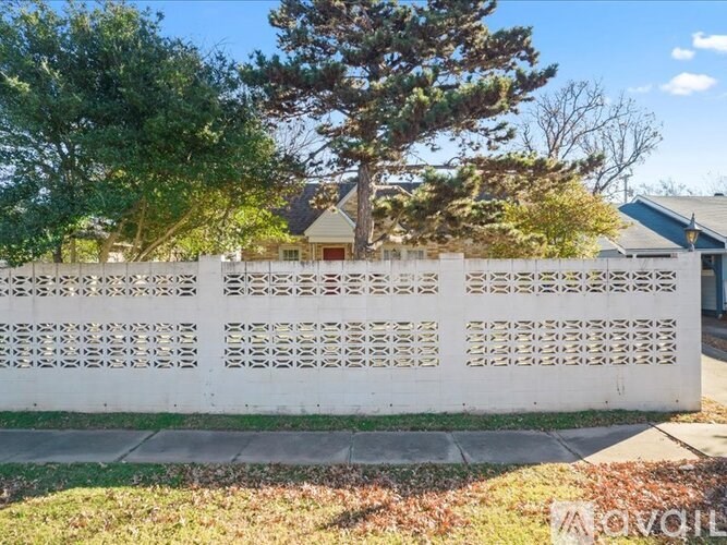 A white fence with a pattern of holes is in front of a house.