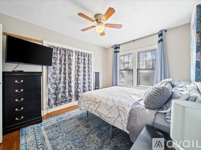 A bedroom with a bed, a dresser, and a ceiling fan.