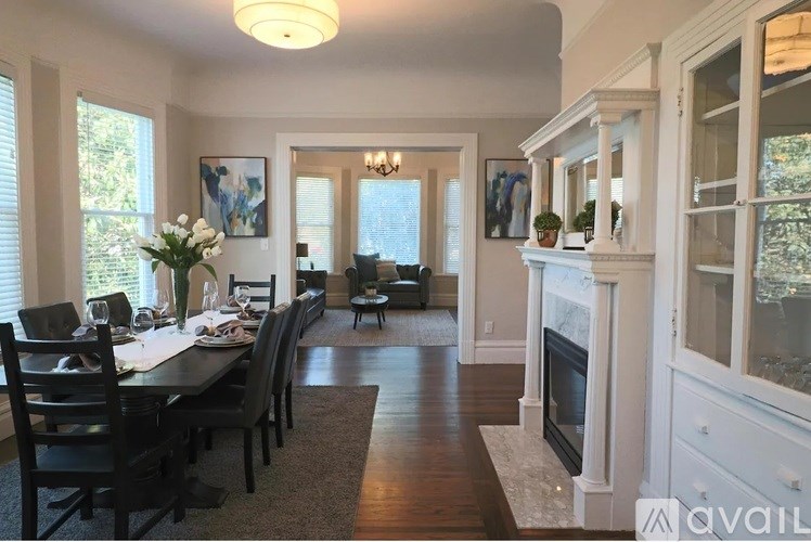 A dining room with a table set for six and a fireplace.