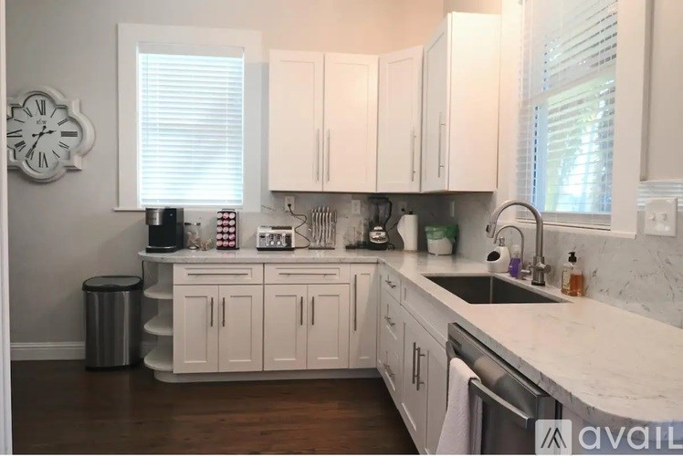A kitchen with white cabinets and a marble countertop.