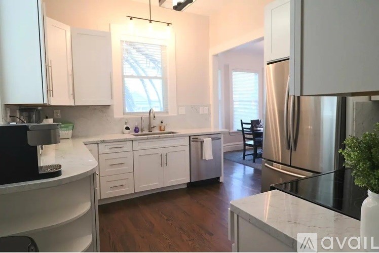 A kitchen with white cabinets and a stainless steel refrigerator.