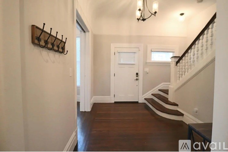 A hallway with a white door and a chandelier.