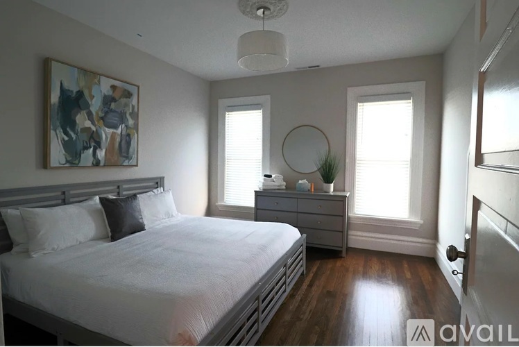 A bedroom with a large bed and a painting on the wall.