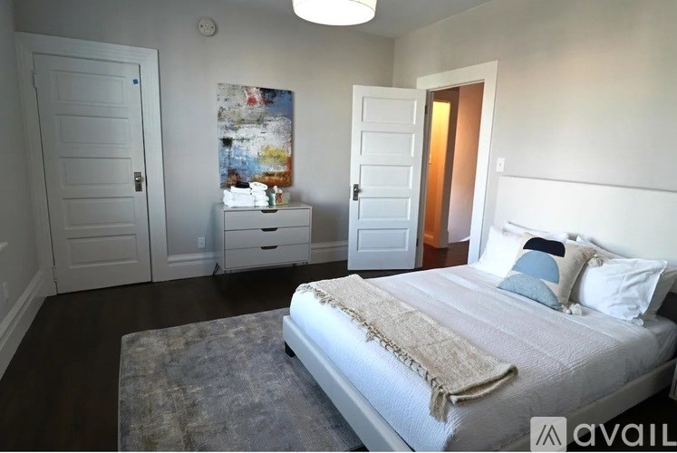 A bedroom with a large bed and a painting on the wall.