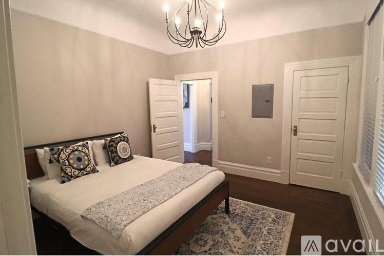 A bedroom with a bed, pillows, and a chandelier.