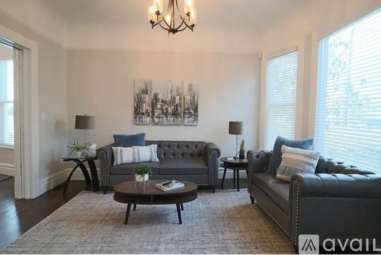 A living room with a grey couch, a coffee table, and a chandelier.