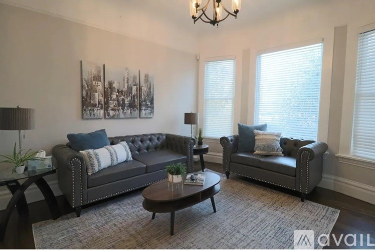 A living room with a grey sofa, a coffee table, and a chandelier.