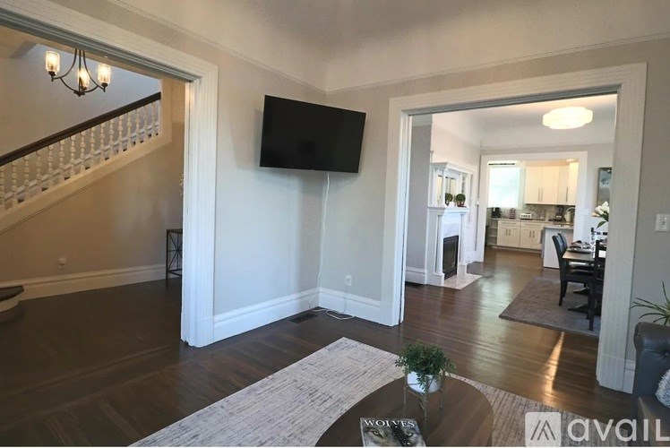 A living room with a TV mounted on the wall and a staircase on the left side.