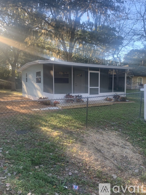 A house with a fence and trees in the background.