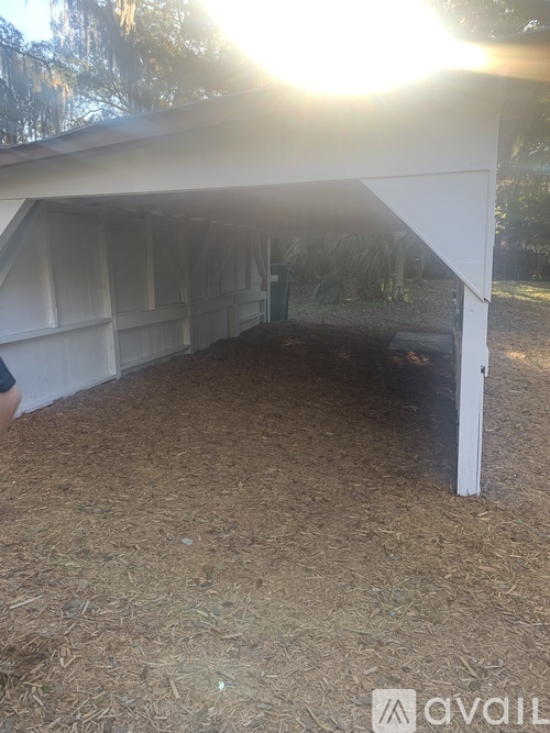 A white building with a roof made of white sheets is in the middle of a field.