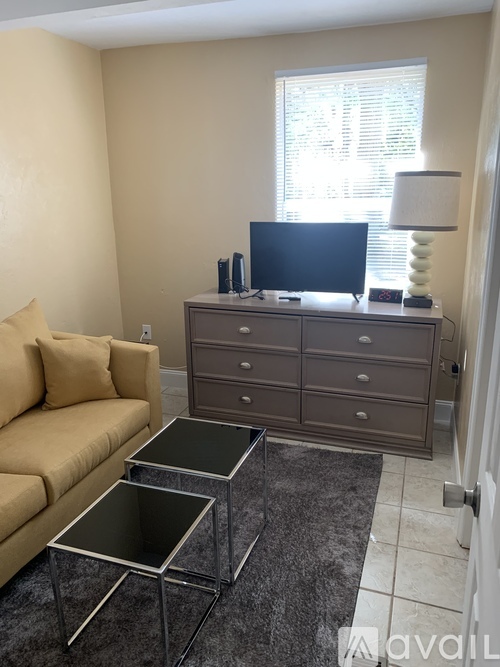A living room with a tan couch, a black TV, and a grey cabinet.