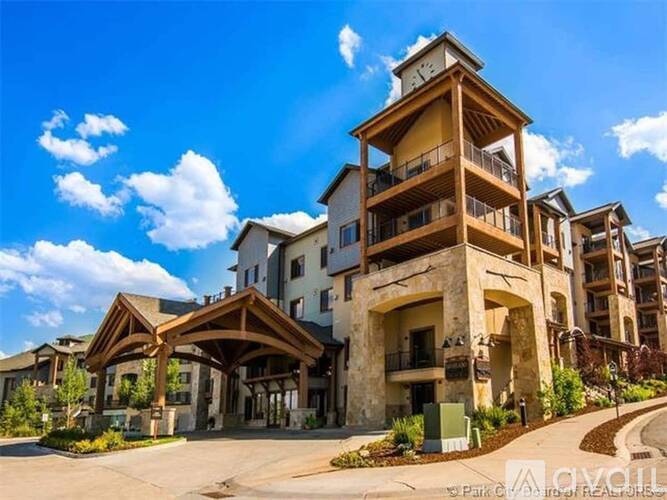 A large, multi-story residential building with a wooden balcony and a clock tower on top.