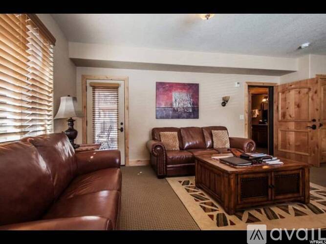 A living room with brown leather furniture and a painting on the wall.