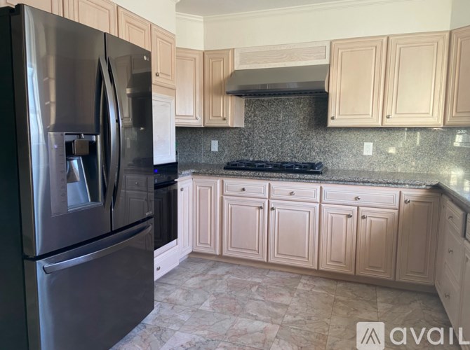 A kitchen with a black fridge and beige cabinets.