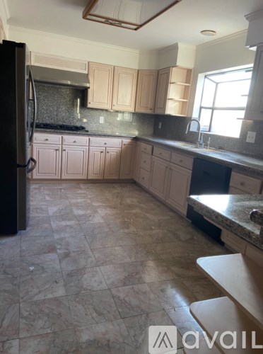 A kitchen with a black refrigerator and wooden cabinets.