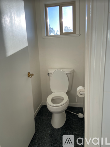 A white toilet in a small bathroom with a window.