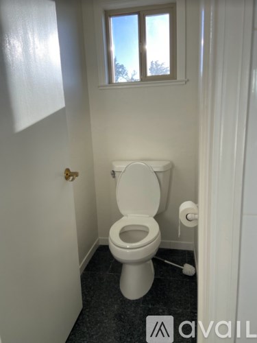 A white toilet in a small bathroom with a window.