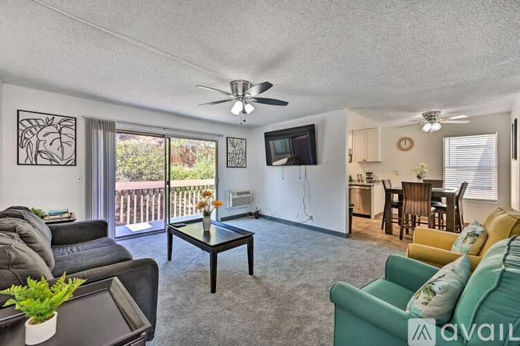 A living room with a black leather couch, a green couch, a coffee table, and a ceiling fan.