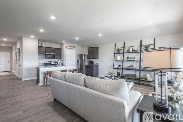 A modern living room with a grey sofa and a kitchen area in the background.