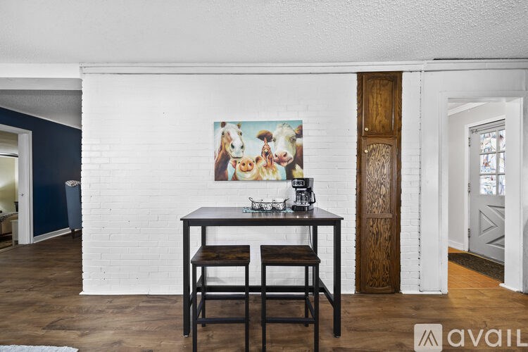 A white brick wall with a painting of cows and a black table with two chairs.