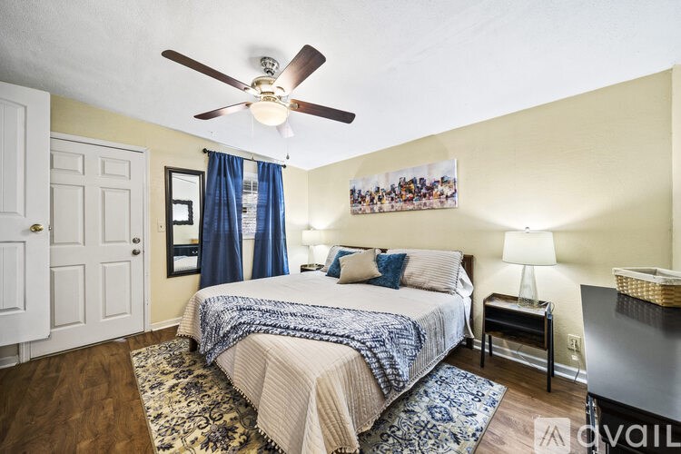 A bedroom with a bed, a ceiling fan, and a picture on the wall.