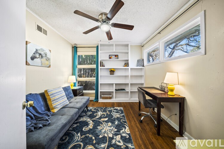 A living room with a blue couch and a ceiling fan.