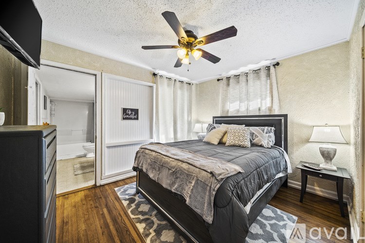 A bedroom with a large bed and a ceiling fan.