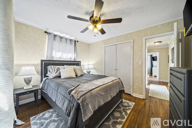A bedroom with a bed, a ceiling fan, and a nightstand with a lamp.
