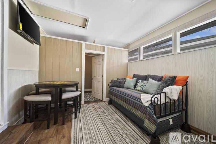 A bedroom with a bed, a table and chairs, and a television.