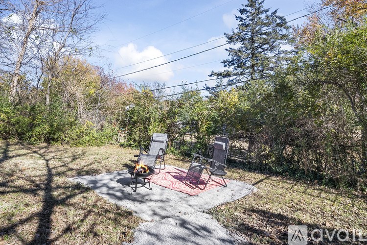 A backyard with a red rug and two chairs.
