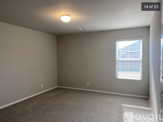 A room with a carpet floor and a window with blinds.
