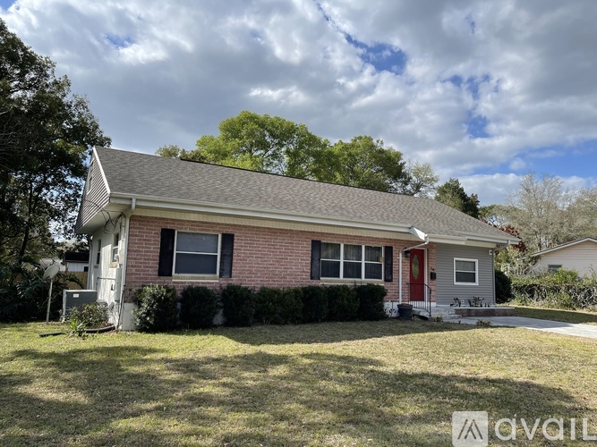 A house with a red door and a grey roof is for sale.
