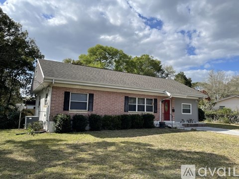 A house with a red door and a grey roof is for sale.