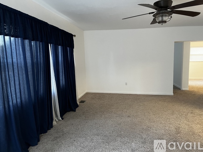 A room with a ceiling fan and carpeted floor.