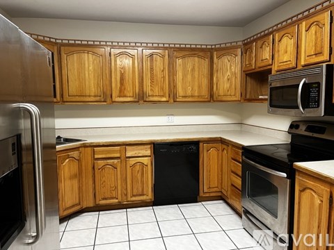 A kitchen with wooden cabinets and a black dishwasher.
