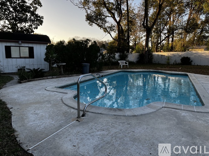 A small above ground pool surrounded by a concrete patio and a white house.