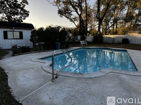 A small above ground pool surrounded by a concrete patio and a white house.