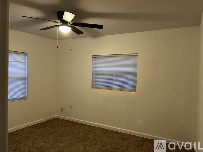 A room with a ceiling fan and two windows.