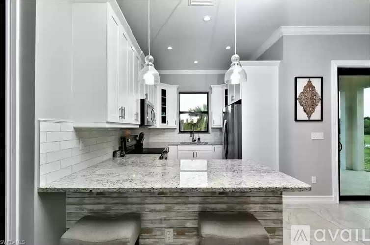 A modern kitchen with a marble countertop and pendant lights.