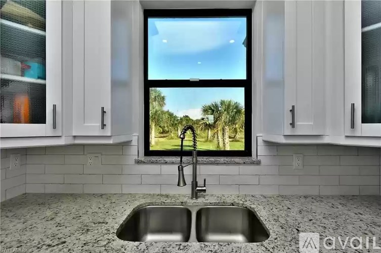 A kitchen with a window overlooking a tree-filled landscape.