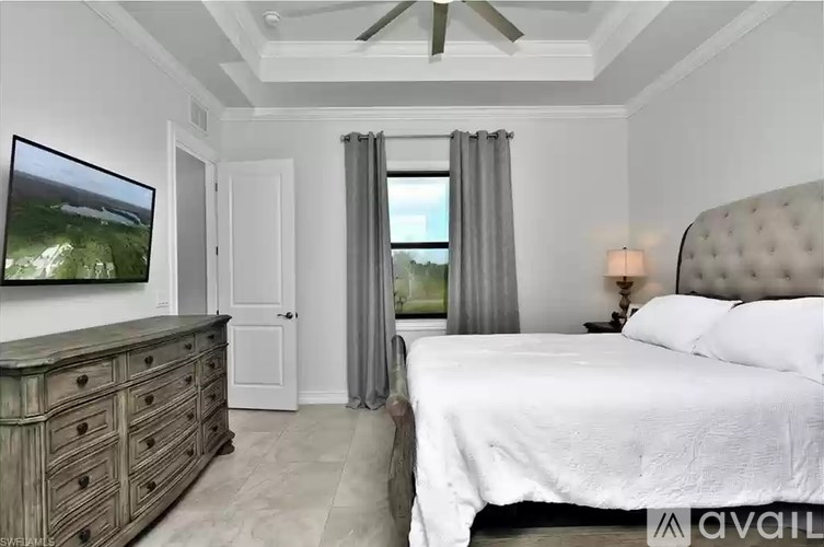A bedroom with a large bed, a dresser, and a painting on the wall.