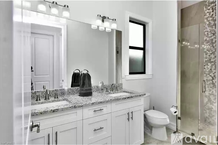 A bathroom with a large mirror, a sink with a marble countertop, and a toilet.