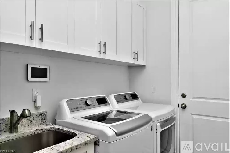 A white kitchen with a washer and dryer stacked on top of each other.