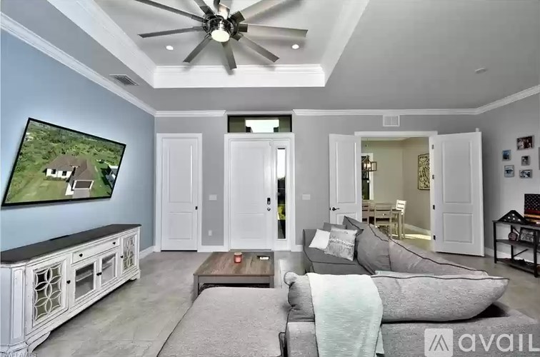 A living room with a grey couch and a ceiling fan.