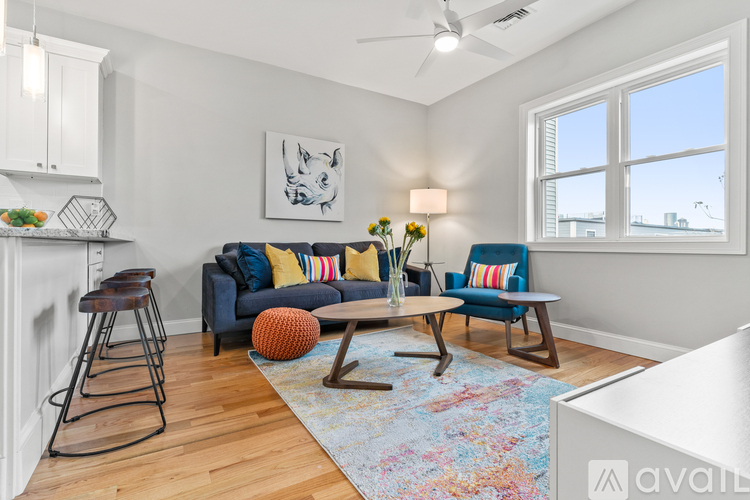 A living room with a blue couch and a rug.
